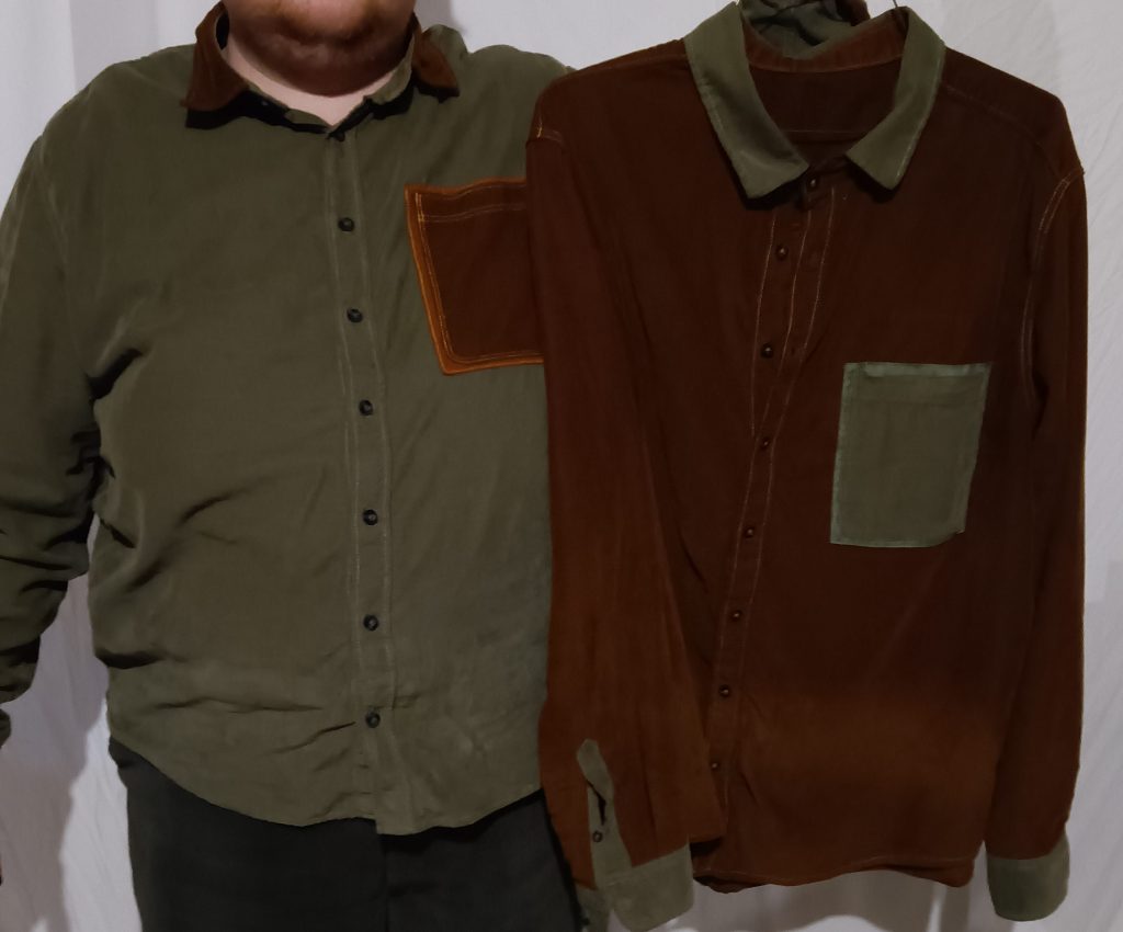 A person wearing a green shirt with amber accents. They are holding an amber shirt with green accents.