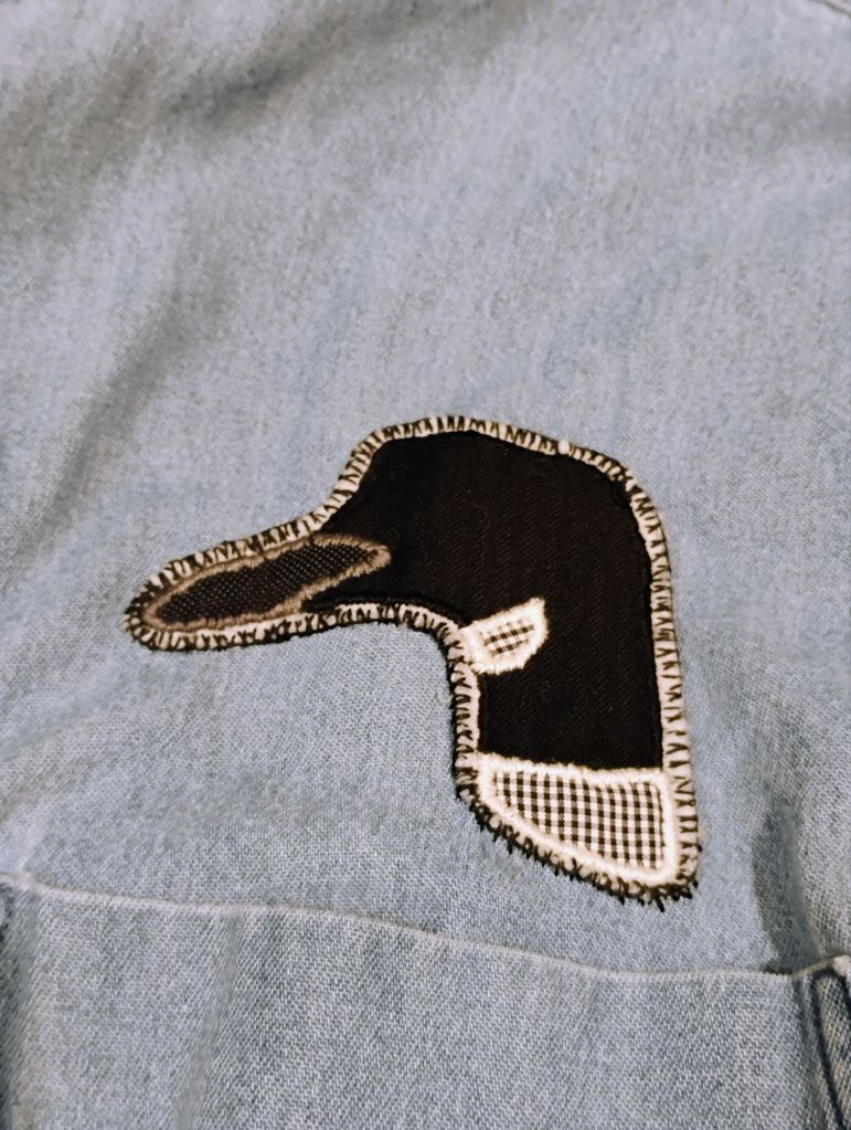 A patch of a loon head on a light blue fabric.
