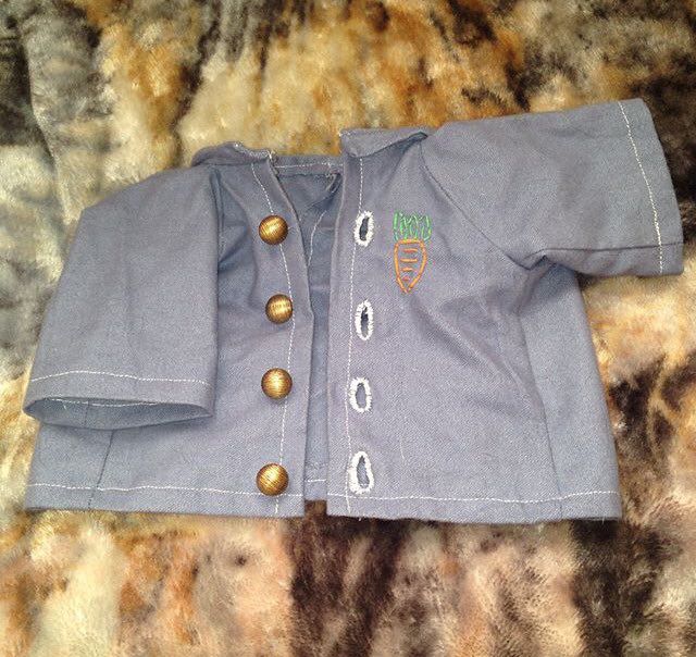 A small blue coat with gold buttons and a carrot embroidered on the top right.