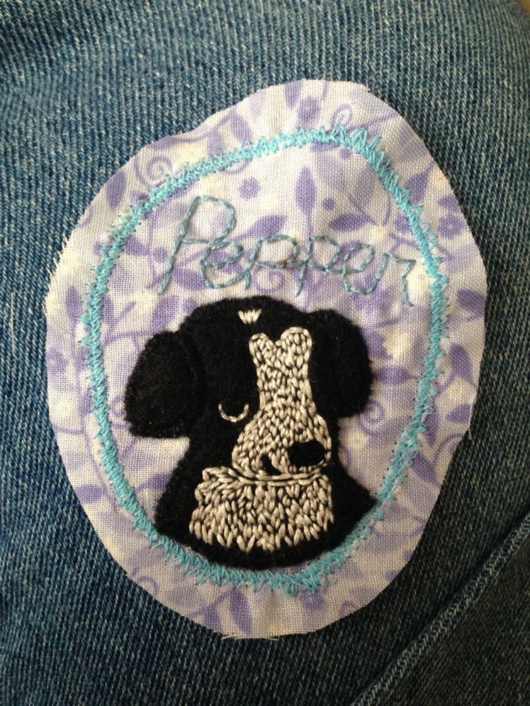An embroidered portrait of a black and white dog named Pepper