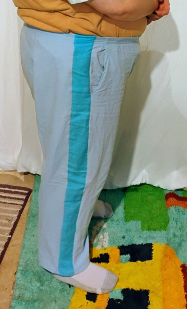 A person wearing a pair of light blue pants with a bright blue stripe down the side