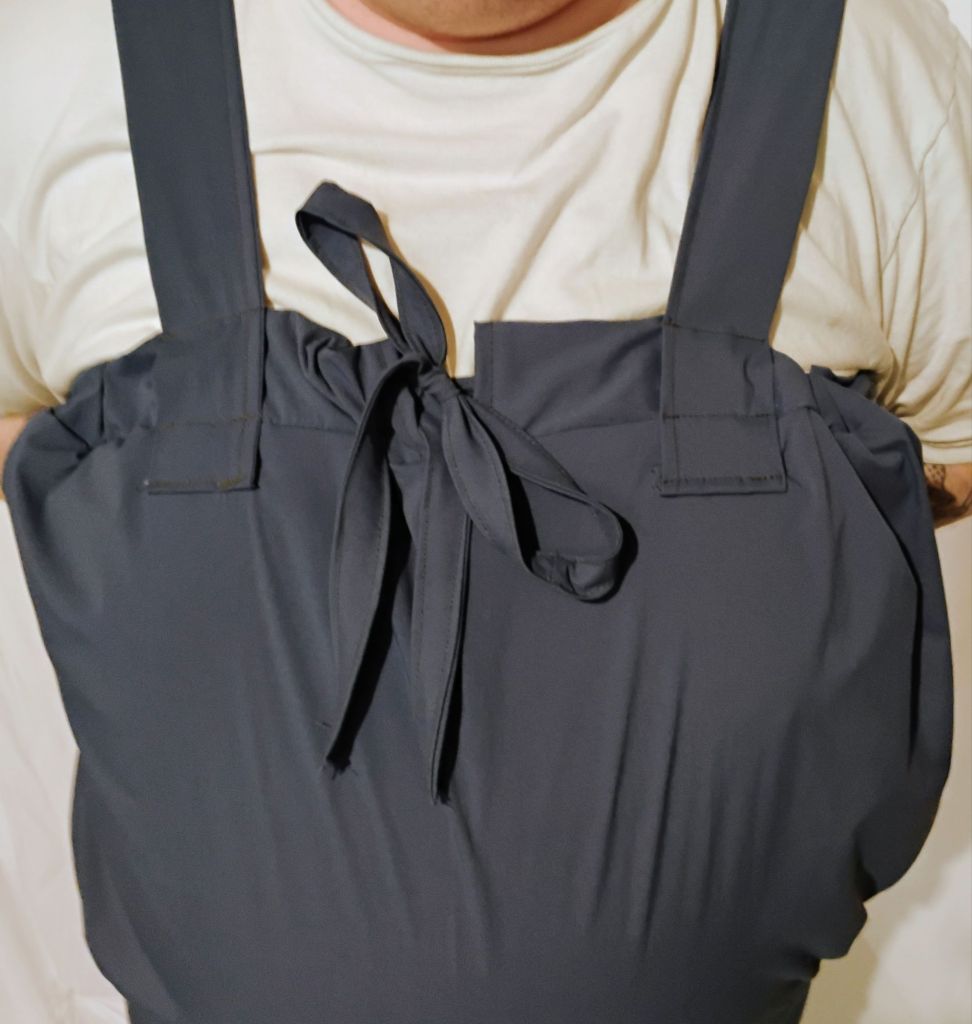 The top of a wetsuit that resembles overalls. it cinches at the top with a drawstring tied in a bow.